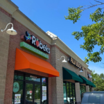 Robeks storefront in Alexandria, VA featuring professional signage with vibrant orange and teal awnings, illuminated wall sconces, and clear brand identification on a mixed-material building facade