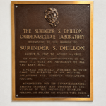 Bronze architectural plaque with raised lettering and dimensional detailing mounted on an interior commercial building wall.